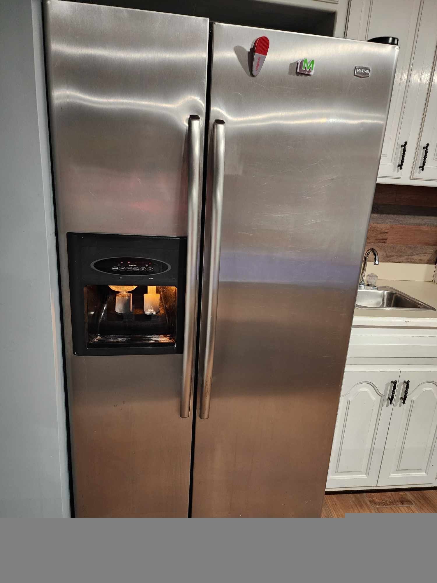 A stainless steel refrigerator is sitting in a kitchen next to a sink.