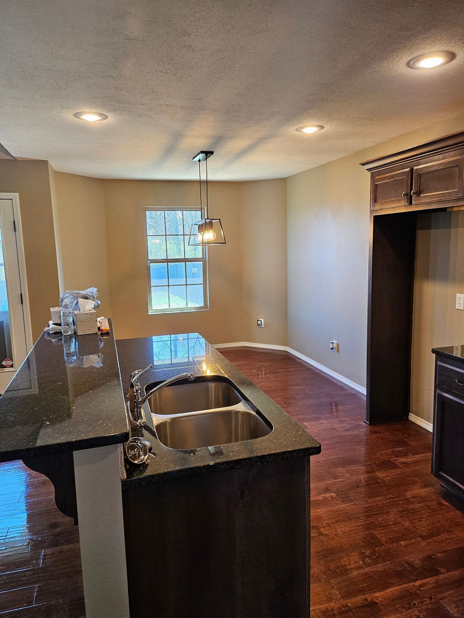 A kitchen with two sinks, granite counter tops, hardwood floors and a window.